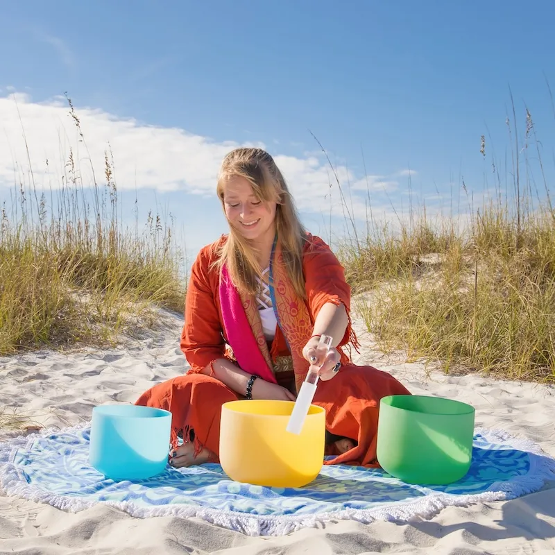 Aarika on the beach using her singing bowls for a sound bath